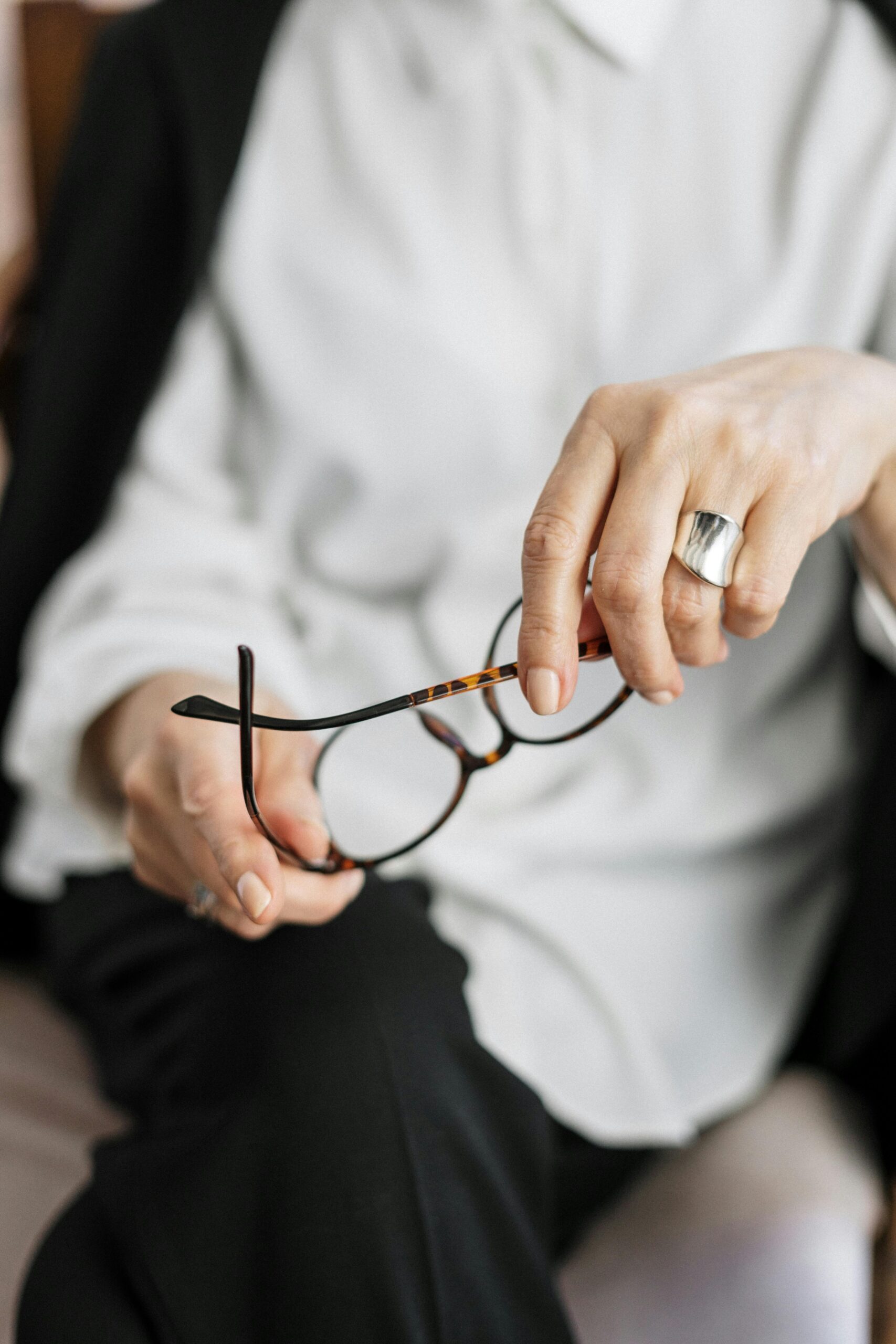 Close-up of a woman holding glasses, symbolizing thought and professionalism.