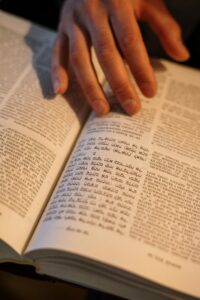 A close-up image of a hand turning pages in a Hebrew religious book, focused on Jewish tradition.